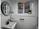 Modern bathroom with white vanity, black fixtures, a round mirror, and a small window at 9390 W Alabama Dr, Lakewood, CO 80232