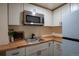 Bright kitchenette with stainless steel appliances, white cabinets, and butcher block countertops at 9390 W Alabama Dr, Lakewood, CO 80232