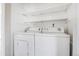 Clean and organized laundry area with white washer and dryer, and open shelving at 381 S Ames St # E305, Lakewood, CO 80226