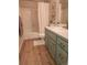 Well-lit bathroom featuring wood-look flooring, tub, and light blue vanity with chrome fixtures at 2190 Coyote Creek Dr, Fort Lupton, CO 80621