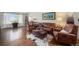 Cozy living room featuring hardwood floors, leather furniture, and a large window with natural light at 2190 Coyote Creek Dr, Fort Lupton, CO 80621