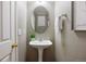 Bathroom with pedestal sink, oval mirror, and white towel hanging on the rack at 6702 S Winnipeg Cir # 101, Aurora, CO 80016