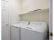 Bright laundry room with side-by-side washer and dryer and storage shelves at 6702 S Winnipeg Cir # 101, Aurora, CO 80016
