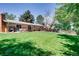 Expansive backyard featuring lush green grass, a patio with seating, mature trees, and partial fencing at 2964 S Akron St, Denver, CO 80231