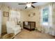 Bedroom with a crib, ceiling fan, armchair, window with light patterned curtains and neutral walls at 2964 S Akron St, Denver, CO 80231