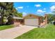 Side view of a brick home with green lawn and a driveway leading to a white two-car garage at 2964 S Akron St, Denver, CO 80231