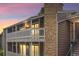 Condo exterior with stone accents, white railing, and well-lit windows at dusk at 18133 E Kentucky Ave # 203, Aurora, CO 80017