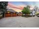 Charming home exterior featuring a well-manicured lawn, stone accents, and a spacious three-car garage, and circular driveway at 18 Club Ln, Littleton, CO 80123