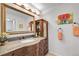 Bathroom vanity with a granite countertop, wooden cabinetry, decorative mirror, and accent art at 10991 Expedition, Littleton, CO 80125