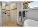 Shower and tub showcasing neutral tile, built-in shelving, and a window for natural light in the bathroom at 10991 Expedition, Littleton, CO 80125