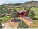 Red home exterior with a large driveway and trees, nestled in a scenic mountain setting at 10991 Expedition, Littleton, CO 80125
