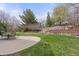 Landscaped backyard features a stone retaining wall, mature trees, and a patio with furniture at 7307 Pine Forest Ln, Parker, CO 80134