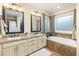 Bathroom featuring double sink vanity, framed mirrors and soaking tub by the window at 7307 Pine Forest Ln, Parker, CO 80134