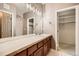 Bathroom offers a long vanity with double sinks, tile countertops, framed mirror, and modern light fixture at 6742 S Winnipeg Cir # 105, Aurora, CO 80016