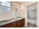 Bathroom with a well-lit vanity, cabinets, and a view into a tiled shower and tub area at 6742 S Winnipeg Cir # 105, Aurora, CO 80016