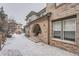 Brick-accented exterior with arched entryway and snow-covered landscaping, adding curb appeal at 6742 S Winnipeg Cir # 105, Aurora, CO 80016