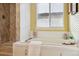 Soaking tub with tiled surround and jets, complemented by a bright window and stylish decor at 15597 E Dorado Ave, Centennial, CO 80015
