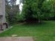 Leafy backyard with mature trees, lush green grass, and unique brick chimney at 13651 Silverton Dr, Broomfield, CO 80020
