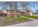 Charming brick home with a well-manicured front lawn, mature tree, and a covered porch, showcasing curb appeal at 1860 W Crestline Dr, Littleton, CO 80120