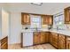A kitchen featuring wood cabinets, stainless steel sink, tile backsplash, and white appliances at 1860 W Crestline Dr, Littleton, CO 80120