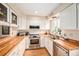 Well-lit kitchen features bright white cabinets, wood countertops, and stainless steel appliances at 10298 W Dartmouth Ave, Lakewood, CO 80227