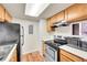 Kitchen features stainless steel appliances, wood cabinetry, and a modern overhead lighting panel at 8335 Fairmount Dr # 102, Denver, CO 80247