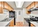 Efficient kitchen featuring stainless steel appliances, wood cabinets, and a modern lighting fixture at 8335 Fairmount Dr # 102, Denver, CO 80247
