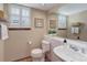 A well-lit half bathroom featuring a white toilet, sink, and tiled walls at 10032 Astoria Ct, Lone Tree, CO 80124