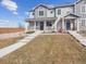 Charming townhome with grey siding, a covered front porch, and stone accents at 16611 E 119Th Ave # E, Commerce City, CO 80022