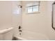 A bathtub with showerhead and white tiled walls, paired with a toilet and a window at 1922 S Oswego Way, Aurora, CO 80014