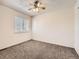 A simple bedroom with neutral carpet, ceiling fan and a window letting in natural light at 1922 S Oswego Way, Aurora, CO 80014