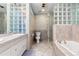 Bright bathroom with glass block accents, double vanity, and separate shower and tub at 2650 S Vaughn Way # B, Aurora, CO 80014