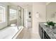 Bright bathroom with a soaking tub, tiled shower, and granite countertops over dark cabinets at 10465 Evansville Cir, Parker, CO 80134