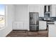 Bright kitchen with stainless steel refrigerator, white cabinetry, and dark backsplash at 2676 W 68Th Ave, Denver, CO 80221