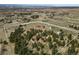 Expansive aerial view of a beautiful property with mature trees, horse facilities, and a charming home in a serene setting at 7076 Inspiration Dr, Parker, CO 80138