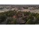 A unique property featuring a sprawling home, mature trees, and city views in the background at dusk at 7076 Inspiration Dr, Parker, CO 80138