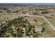 A high angle aerial showcases the property with horse facilities, buildings, and a home nestled among trees and open land at 7076 Inspiration Dr, Parker, CO 80138