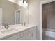Bathroom featuring a double sink vanity, large mirror, and tiled shower at 7022 Homeplace St, Castle Rock, CO 80108