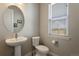 Charming powder room with a pedestal sink, round mirror, and a window offering natural light at 7022 Homeplace St, Castle Rock, CO 80108