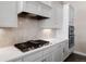 Modern kitchen with built-in stainless steel oven and gas range on white countertop and backsplash at 7022 Homeplace St, Castle Rock, CO 80108