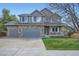 Charming two-story home featuring a stone facade, attached garage, and a covered porch, complemented by a well-maintained lawn at 13330 York Way, Thornton, CO 80241