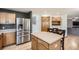 Modern kitchen featuring stainless steel fridge, wooden cabinets, center island, and hardwood floors, offering great flow at 13330 York Way, Thornton, CO 80241