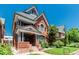Angle view of the brick home featuring a detailed covered front porch and manicured green lawn at 931 E 17Th Ave, Denver, CO 80218