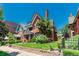 Quaint brick home showing a well-manicured lawn and garden, mature trees, and charming architectural details at 931 E 17Th Ave, Denver, CO 80218