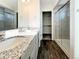 Modern bathroom featuring dual sinks, granite counters, a glass shower door, and stylish gray cabinets at 17908 E 54Th Ave, Denver, CO 80249