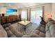 Bright living room featuring hardwood floors, gray couches, tray ceilings, and a decorative rug at 17908 E 54Th Ave, Denver, CO 80249