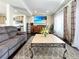 Bright living room featuring hardwood floors, gray couches, a wooden cabinet, and gray kitchen accents at 17908 E 54Th Ave, Denver, CO 80249