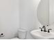 Modern powder room features a white toilet, pedestal sink, and round mirror with matte black fixtures at 8376 Cokedale Dr, Littleton, CO 80125