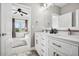 Bright bathroom featuring a double vanity, gray walls, and a view into a bedroom with a ceiling fan at 5582 Twilight Way, Parker, CO 80134