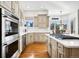 Gourmet kitchen featuring stainless steel appliances, a large island, light colored cabinets, and hardwood flooring at 5582 Twilight Way, Parker, CO 80134